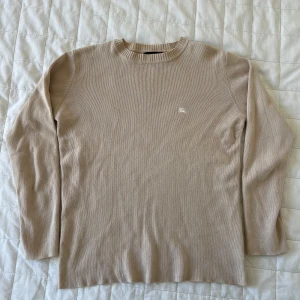 Beige tröja Burberry - Säljer en stilren beige tröja från Burberry i 100% bomull. Tröjan har ett diskret broderat märke på bröstet och ribbade kanter vid halsen. Perfekt för en klassisk och avslappnad look. Sitter typ som en xs. Lite skador vid halsen, kan skicka bilder närmare om det behövs. Annrs prima. Burberrys barn line-up, så det är därför labeln säger CWF. De tillverkade barnkläderna till de flesta lyxmärkena. Passar bäst till kvinna eller barn. 