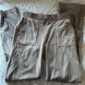 Beige mjukisbyxor från Juicy Couture - Snygga beige mjukisbyxor från Juicy Couture med elastisk midja och snörning. Storlek XS. Byxorna har praktiska fickor fram och bak med knappar. Perfekta för en avslappnad stil. Säljer då dom inte kommer till andvändning längre💕 Använd ett par gånger men fortfarande i super bra kavalite. PRIS KAN DISKUTERAS!!