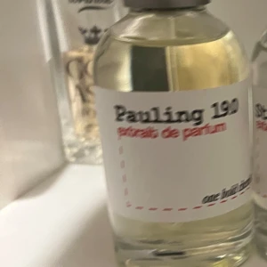Pauling 190 Extrait de Parfum (OBC) - Säljer en exklusiv flaska Pauling 190 Extrait de Parfum. Flaskan är genomskinlig med en enkel vit etikett och svart text. Perfekt för den som söker en unik doftupplevelse.