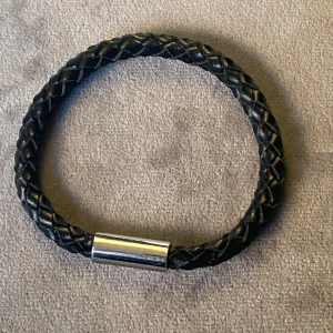 Svart flätat armband med metallspänne från Edblad!  - Snyggt svart flätat armband med ett stilrent metallspänne. Perfekt accessoar för en modern look. Mycket bra skick! Magnetlås. Vikt 7 gr totala längd inkl lås 21,5 cm