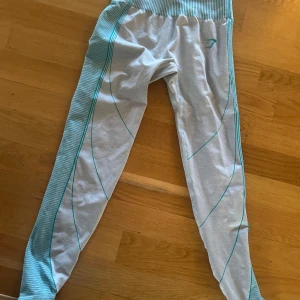 Gymshark träningstights - Snygga grå träningstights med turkosa detaljer och ribbad midja. Perfekta för gymmet eller yoga. De har en tight passform och är gjorda i ett stretchigt material för bästa komfort.