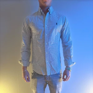 Rutig skjorta från Ralph Lauren - Snygg rutig skjorta från Ralph Lauren i blått och vitt.  klassisk krage med knappar framtill. Perfekt för en stilren look.