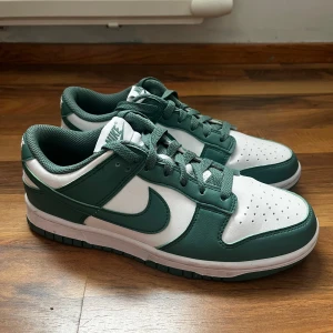 Nike low Dunk next nature - Skorna är endast använda 3 gånger. Superfint skick. Färgen plockas inte upp så väl av kameran men det är en superfin mörkgrön/turkos liknande färg som är perfekt till våren och sommaren!