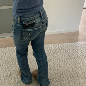 Blå jeans med bootcut - Snygga blå jeans med bootcut-stil och låg midja. De har en klassisk femficksdesign och slitna detaljer som ger en trendig look. Perfekta för en avslappnad stil.