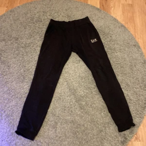 Svarta mjukisbyxor från Emporio Armani - Tja! säljer nu mina Snygga svarta mjukisbyxor från Emporio Armani med EA7-logga på benet. Perfekta för en avslappnad stil. Byxorna har en elastisk midja och sidofickor för extra komfort.Dessa är Limited edition exakt som EA7 hoodien. Kan gå ner i priset