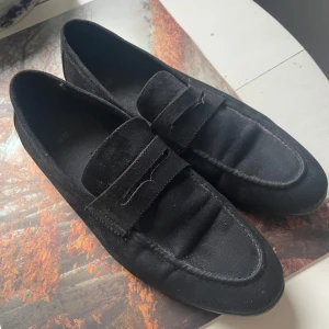 Svarta loafers i mocka - Snygga svarta loafers i mocka med en stilren design. Perfekta för en elegant look. Skorna har en klassisk form och är tillverkade i ett mjukt material för extra komfort.