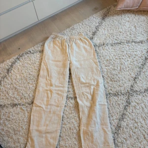 Beige linnebyxor från Design by Si - Snygga och bekväma beige linnebyxor från Design by Si. Byxorna har en elastisk midja. Använda ett fåtal gånger. Säljer då dom inte kommer till användning, hör av dig om du har frågor💘