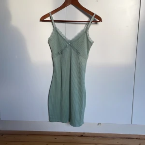 Grön ribbad klänning med spetsdetaljer i nyskick - Säljer en grön gibbad klänning med spetsdetaljer i nyskick.