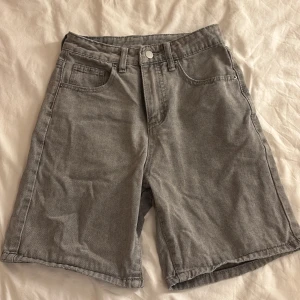 Grå jorts  - Säljer ett par grå jeansshorts med knappgylf. Perfekta för en avslappnad stil. De har en normal passform och är tillverkade i slitstarkt denim. aldrig använda 