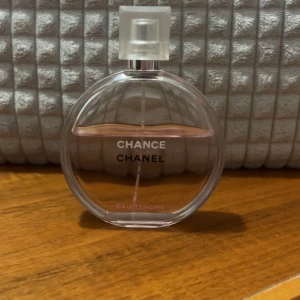 Chance Eau Tendre från Chanel - Säljer en elegant och feminin parfym, Chance Eau Tendre från Chanel. Flaskan är rund och genomskinlig med en ljusrosa vätska inuti. Den har en stilren design med en fyrkantig, frostad kork. Perfekt för den som älskar en fräsch och blommig doft. 100ml
