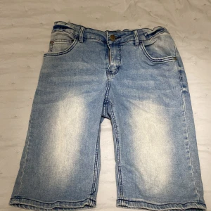 Ljusblå jeansshorts från LAB Industries - Säljer ett par ljusblå jeansshorts från LAB Industries. De har en klassisk femficksdesign med knapp och dragkedja framtill. Shortsen har en avslappnad passform och är perfekta för varma dagar. Märket LAB Industries är tryckt på insidan av linningen. Det finns även resor i midjan som man kan ställa in själv.