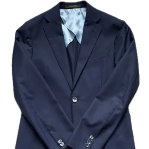 Mörkblå kostym i Drago super 160s - Elegant och tidlös mörkblå kostym från Oscar Jacobson. Materialet är Dragos exklusiva 160s ull. Modell Einar med klassiska patch pockets och okonstruerade axlar. Både byxa och kavaj i motsvarade strl 44. Perfekt för dig som vill ha en fin examenskostom eller vara bäst klädd inför sommarens alla tillställningar. Hör av dig om du är intresserad eller har några frågor! 