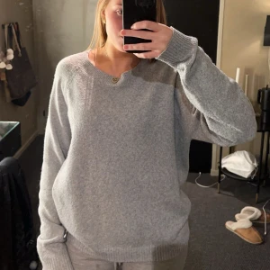 Grå stickad tröja - Mysig grå stickad tröja med rund halsringning och långa ärmar. Perfekt för kyligare dagar och enkel att matcha med olika outfits.