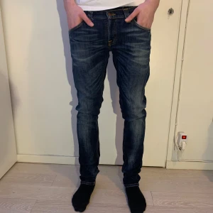 Mörkblå jeans från Nudie Jeans - Vi säljer ett par mörkblå jeans från Nudie Jeans i passform slim. Jeansen har en riktig skön fade vilket ger en levande känsla till varje outfit som jeansen bärs i. Ett klart val i vilken garderob som helst! Modellen är 184 cm och väger 69 kg