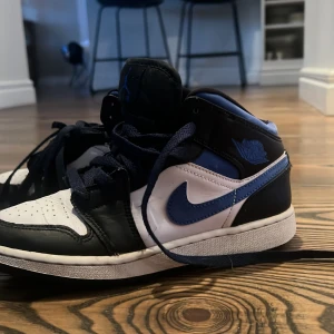 Nike Air Jordans i svart och blått - Snygga Nike Air Jordans i svart och blått med vit sula. Skorna har klassisk snörning och en stilren design som passar perfekt för streetwear. Perfekta för dig som vill ha en sportig look med stil.