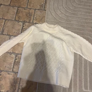 Vit stickad tröja från 157 - Säljer en mysig vit stickad tröja från 157. Tröjan har ett fint kabelstickat mönster och långa ärmar. Perfekt för kyliga dagar. Hör av dig vid intresse! 🤍