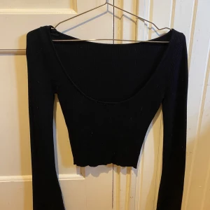 Svart ribbad croppad topp - Snygg svart ribbad topp med långärmad design och croppad passform. Perfekt för en stilren look. Passar xxs-s,använd en eller två gånger