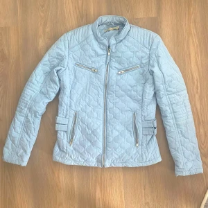 Ljusblå quiltad jacka från First Class - Säljer en superfin ljusblå quiltad jacka från First Class. Den har en snygg dragkedja framtill och två dragkedjefickor på bröstet. Jackan är i storlek 36 och har en cool, lite sportig look. Perfekt för vår och höst!