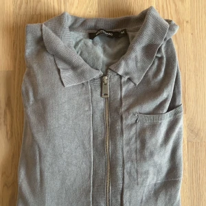 Grå tröja med dragkedja från Bolongaro Trevor - Säljer en stilren grå tröja/kofta från Bolongaro Trevor i storlek M. Snygg och bekväm i material! Passar ej mig så aldrig använd. Nypris 1.399kr. Mitt pris 149kr.
