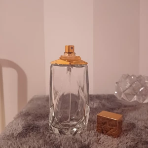 Parfym -     TOM !!!Säljer en stilren och elegant parfymflaska i glas med ett lyxigt guldlock. Flaskan rymmer 100 ml och har en modern design med mjuka kurvor. Perfekt för att ge en touch av elegans till din parfymkollektion. Flaskan är tom och redo att fyllas med din favoritdoft. Perfekt för både vardag och speciella tillfällen. 💫