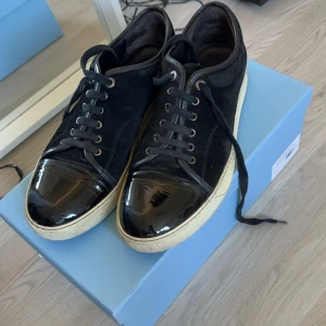 Lanvin Cap toe  - Säljer ett par svarta Lanvins i bra skick förutom en liten defekt på captoen på höger sko (syns på bild 1). Låda, dustbag, nya skosnören ingår. Storlek 9uk eller 43 (stora i storleken).  Hör av dig vid funderingar!