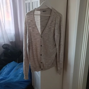 Grå kofta med knappar - Säljer en mysig ljusgrå kofta med knappar. Perfekt för lager-på-lager under hösten. Den har en normal passform och är långärmad, vilket gör den superbekväm att ha på sig. Koftan är i bra skick.