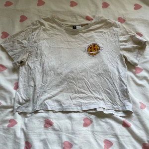 pizza t-shirt  - vit t-shirt med en pizza på bröstet där det står ”saving the world one slice at the time”. materialet har mörknat lite efter användning samt tvättning 