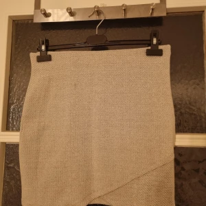 Grå kjol från Gina Tricot - Grey skirt from Gina Tricot size L. Small stain thats barely visible because of the pattern. All items have been stored in a box and need to be washed by the buyer .