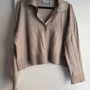 Beige tröja från Weekday - Säljer en superfin beige tröja från Weekday i storlek XS. Den är gjord av en mjuk blandning av modal, polyester och polyamid, vilket gör den både bekväm och hållbar. Tröjan har en klassisk krage och långa ärmar, perfekt för både vardag och lite mer uppklädda tillfällen. Den är i nyskick och redo för en ny ägare!