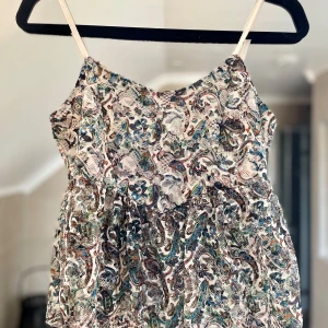 Mönstrad ärmlös spets topp - Säljer en superfin spets topp med ett färgglatt paisleymönster. Toppen har smala axelband och en luftig passform. I fint skick!❤️