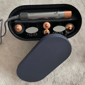 Hårstyler med tillbehör i elegant förvaringsbox - Säljer en snygg och praktisk hårstyler med flera tillbehör, perfekt för att skapa olika frisyrer. Den kommer i en elegant mörkblå förvaringsbox. Verktyget har en modern design med grå och kopparfärgade detaljer. Perfekt för både vardag och fest!