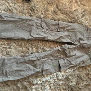 Grå cargobyxor - Säljer ett par grå cargobyxor i bra skick. De har flera praktiska fickor på sidorna och är perfekta för en avslappnad stil. Byxorna är tillverkade i ett slitstarkt material och passar bra för både vardag och utomhusaktiviteter.