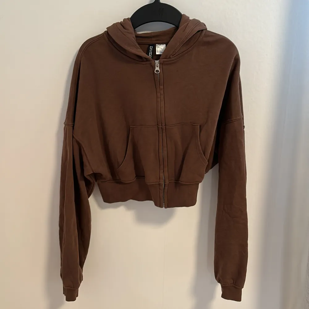 En brun croppad luvtröja från H&M Divided. Den har en dragkedja framtill och fickor. Nyskick!. Neuletakit & Villapaidat.