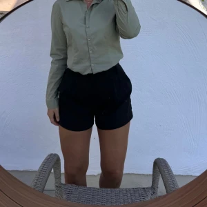 Olivgrön skjorta med knappar - Säljer en stilren olivgrön skjorta med knappar framtill. Skjortan har en klassisk krage och långa ärmar, perfekt för både vardag och lite mer uppklädda tillfällen. VÄLDIGT liten i storleken