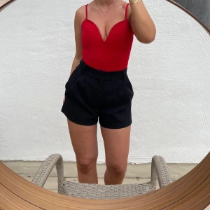 Röd bodysuit från Boohoo - Säljer en snygg röd bodysuit från Boohoo. Den har smala axelband och en djup v-ringning som ger en elegant look. Perfekt för festliga tillfällen eller en utekväll. Liten i storleken