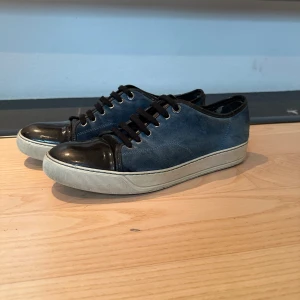 Lanvin Skor - Säljer dessa blå Lanvin skor. Skorna är väl använda och har defekter (se bild 4 och 5). Bortsätt från dessa defekter är skorna i relativt fint skick, därav priset. Nypris är ca 4500kr. Skriv vid frågor eller funderingar!