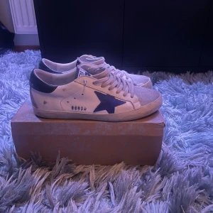 Golden goose - Golden goose säljes i storlek 44! Skorna är använda varsamt och jag skulle säga att skicket är 8/10. Däremot finns det en liten defekt under sulan som visas på bild 3. Skorna är äkta, box ingår. Hör gärna av er angående frågor eller funderingar🥂