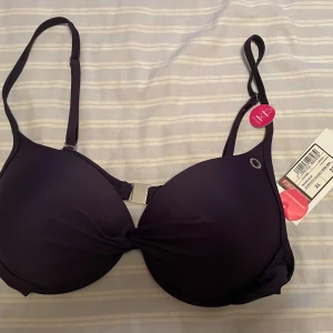 *NY*Mörkblå Röhnisch bikiniöverdel i stl XL - Ny överdel ”Blanca Wire Bra” med snygga detaljer i silver! Två funktioner, går att ha bhband vanligt/korsat i ryggen. Uppskattar den passar bäst på D-kupa, ca 80/85 D. Passar ej mig som har E/F kupa. Material; 82%polyamid, 18% elastan. Svensk design.