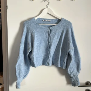 Ljusblå kofta från Zara - Säljer en superfin ljusblå kofta från Zara. Den är stickad och har en mysig känsla, perfekt för kyliga dagar. Koftan har långa ärmar och knappar framtill. Den är i bra skick och passar perfekt till både vardag och fest!