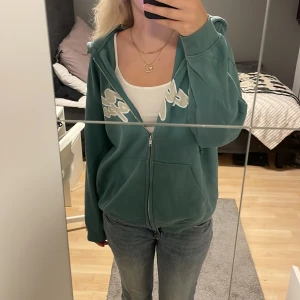 Zip hoodie - En super fin grön zip hoodie med tryck på som inte längre kommer till användning. Inga defekter bara att skriva för fler frågor och funderingar💕