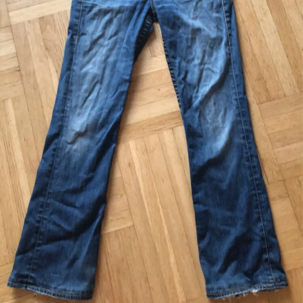 Säljer ett par snygga blå jeans från True Religion i storlek M. De har en cool tvättad look och detaljerade bakfickor med knappar. Jeansen har en låg midja och är flare . Jeans & Byxor.