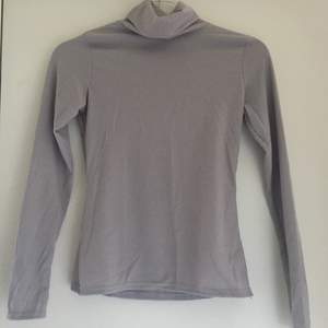 Fin grå basic långärmad tröja med turtle neck i strl 38. På bilderna så kan man se både fram och baksidan, tröjan är i nytt skick och har aldrig använts.