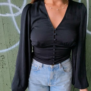 Svart topp - Säljer denna jättefina svarta toppen i storlek small🖤 Toppen är i silkesmaterial med puffiga armar och korsetliknande-design i midjan. Använd ett fåtal gånger så är i princip i ny skick✨✨ 