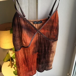 Linne  - Snyggt linne som feadar i brunt och oranget. Med bruna/läder detaljer vid banden och runt brösten. Även glitter fastsytt runt hela toppen:) 