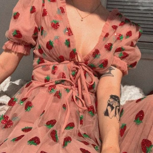 Viral Strawberry Dress by lirikaMatoshi - Den kända och virala Strawberry klänningen designad av lirikaMatoshi. Endast använd en gång och är i perfekt skick, lite av glittret på jordgubbarna har trillat av men ingenting som alls är synligt på plagget. Den är true to size och är enkel att ha på sig. Köpt för 5,000kr exklusive fraktavgifter och säljs därefter för 2.000kr.  Önskas fler bilder är det bara att skriva. (pris kan gå att diskutera)