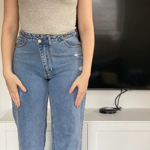 Blåa jeans  - Blå jeans, slitningar vid fötterna. 