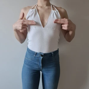 Vit halterneck topp med snörning - Denna vita toppen bar min mamma när hon var ung! Skön, luftig, halterneck toppmed justerbar snörning. Perfekt ovanpå bikinin eller bara snygg och skön att ha utan behå under. Har en likadan i svart.