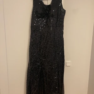 Svart festklänning.  - Använd endast en gång. Storlek L men passar även större storlek då det är en snörning. Väldigt fin oxh i nytt skick. Frakten ingår i priset. 