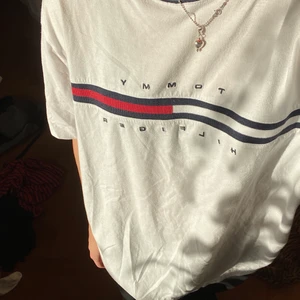 Tommy Hilfiger t-shirt  - Overzised Tommy hilfiger tröja som är köpt second hand. Storlek XL, så den är för stor på mig. Finns en liten fläck på baksidan (se bild). På framsidan finns också en liten fläck som inte syns när man använder tröjan. Kan skicka bild på fläckarna till den som undrar. Kan mötas upp i Malmö om du vill testa tröjan innan du köper.