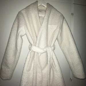 Vit kappa från Nelly - En vit nästan oanvänd kappa från Nelly i storlek 34. Den sitter inte heltight så man kan ha en tjockare tröja under. Jag har använt den en gång sen den köptes så den är nästan helt oanvänd. Inga fel på den som smuts eller hål eller något annat. Som helt ny.
